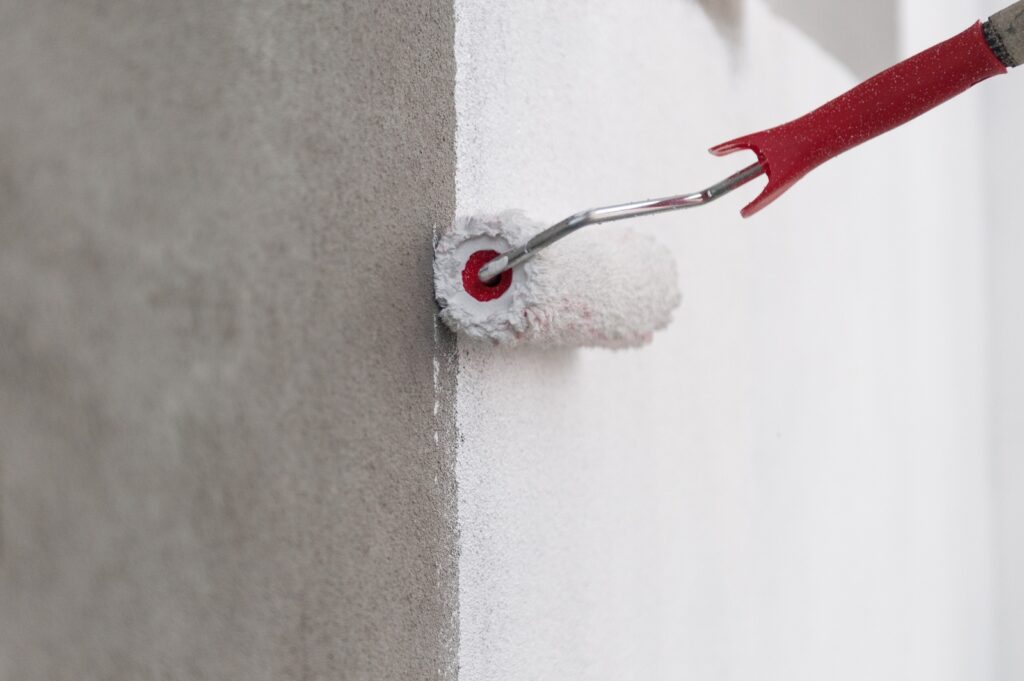 Paint Roller Applying White Coat On Exterior Wall For Residential Painting And Wall Preparation